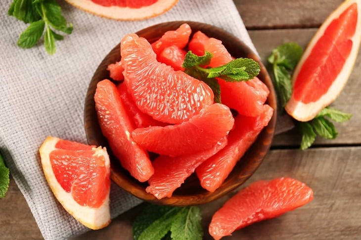 Juicy grapefruit pieces with fresh mint in a bowl, close up