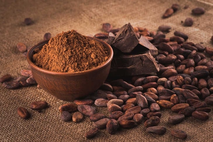 Raw cocoa beans, clay bowl with cocoa powder, chocolate on sacking