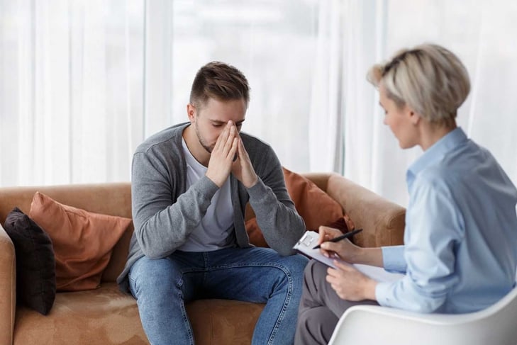 Depression Counseling. Desperate Man Telling About Unhappy Life While Professional Psychologist Taking Notes During Appointment In Office. Selective Focus