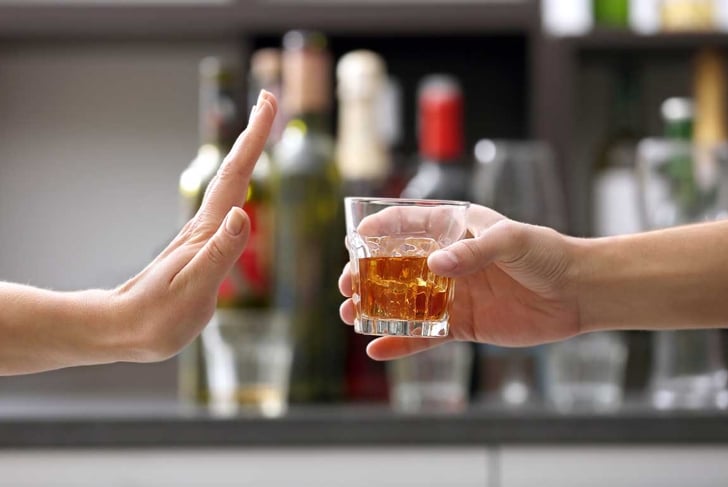 Female hand rejecting glass with alcoholic beverage on blurred background