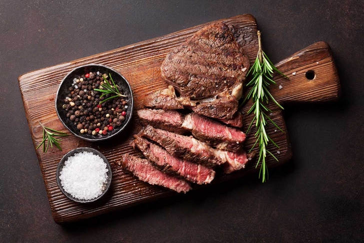 Grilled beef steak with spices on cutting board. Top view