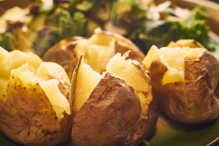 Hot buttered jacket baked potatoes close up with steam