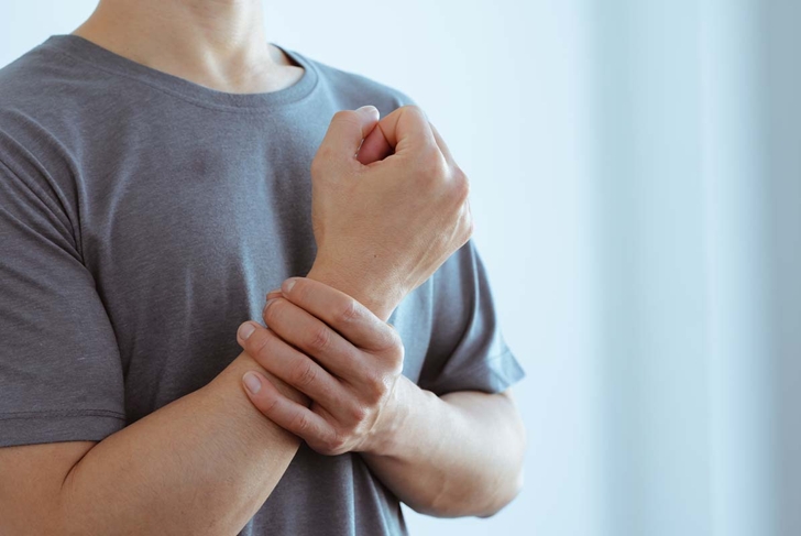 male arms holding his painful wrist caused by prolonged work on the computer, laptop,neurological disease concept. Numbness of the hand