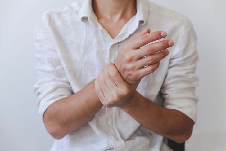 Closeup of male arms holding his painful wrist caused by prolonged work on the computer, laptop.Carpal tunnel syndrome, arthritis, neurological disease concept. Numbness of the hand