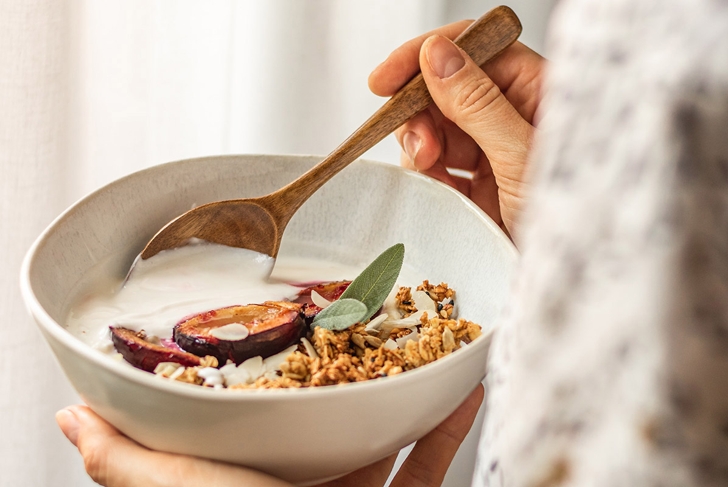 girl holding oatmeal fruit white bowl with yogurt and granola