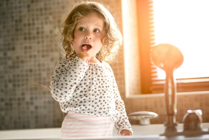 The baby brushes his teeth in the morning in a bathroom